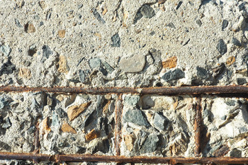 Texture and background of a concrete block with sticking stones and pieces of reinforcement...
