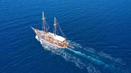 Aerial birds eye drone view of beautiful wooden sailboat in deep blue sea of island of Mykonos, Cyclades, Greece