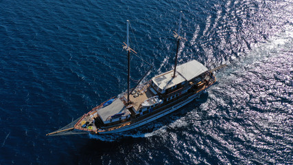Aerial birds eye drone view of beautiful wooden sailboat in deep blue sea of island of Mykonos, Cyclades, Greece