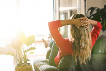 Woman relaxing in armchair at home at the window