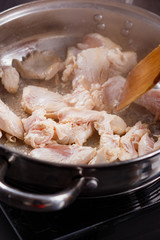 young woman in a gray aprons roasts chicken fillet with carrots
