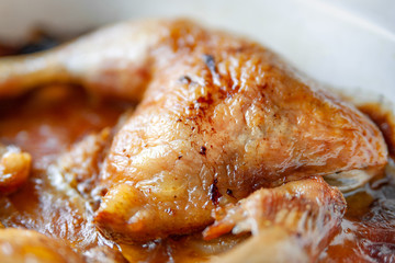 Baked chicken legs in their own juice close-up in a baking dish.