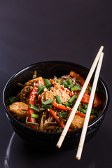 Buckwheat noodle in a black bowl on chicken fillet