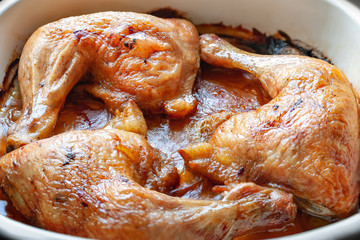 Baked chicken legs in their own juice close-up in a baking dish.