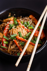 Buckwheat noodle in a black bowl on chicken fillet