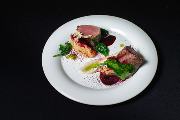 Beef steak with mashed potatoes decorated with greens on a white plate.