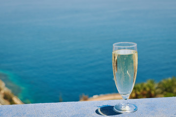 Glass of white dry wine over seaside background, summertime.