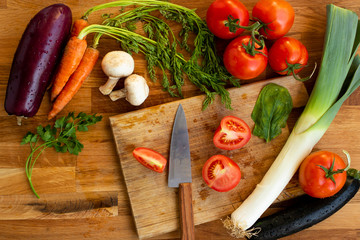 vegetables, carrots, greens, tomatoes, onions, eggplants lie on a wooden table, the concept of vegetarian
