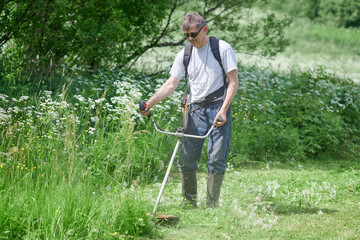 Country works on the personal plot using grass trimmer.