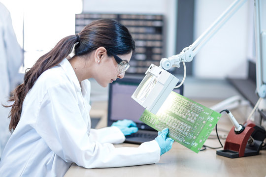 Female technician examining motherboard - Powered by Adobe