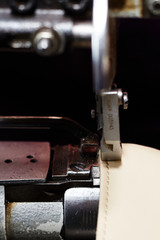 A woman sews a leather strip with a special sewing machine for leather, used in the production of handbags / shoes