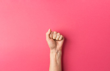 Young caucasian woman's hand with clenched fist on fuchsia pink background. Women power independence freedom equality fighting for rights concept. Trendy funky style. Poster template