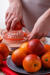 young woman in a gray apron squeezes juice of orange blood