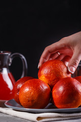 young woman in a gray apron takes blood orange