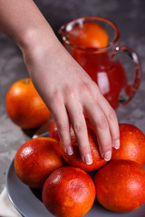 young woman in a gray apron takes blood orange