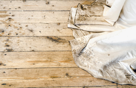 Detail view of beautiful white wedding dress train after outdoor wedding in rainy day on wooden board background. Needing a dry cleaning concept.