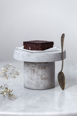 Vegan raw brownies with nuts and dates, on white marble background with copy space. Healthy dessert concept