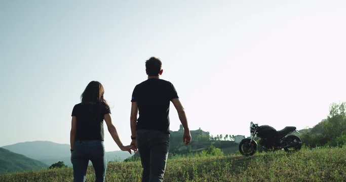 In amazing beautiful landscape young couple arrived with their motorcycle and exploring the place in a summer hot day.