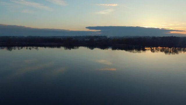 Romantic water landscape with sunset sky. Smooth surface of the wide river with reflection. Calm quiet weather. Aerial survey- flight of drone 