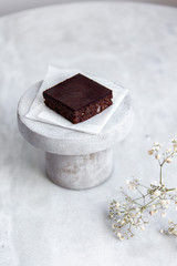 Vegan raw brownies with nuts and dates, on white marble background with copy space. Healthy dessert concept