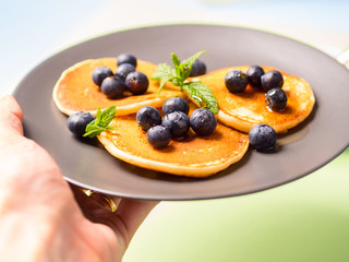 Pancakes served with fresh blueberries on gray plate over geometrical background. Healthy home made breakfast concept
