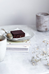 Vegan raw brownies with nuts and dates, on white marble background with copy space. Healthy dessert concept