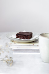 Vegan raw brownies with nuts and dates, on white marble background with copy space. Healthy dessert concept