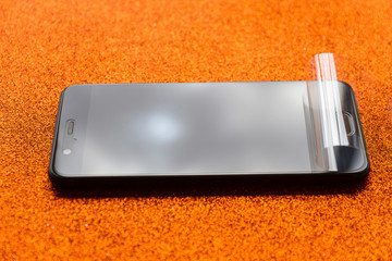 Smartphone nuevo con plastico protector de pantalla, a medio quitar, antes de ser estrenada. ...
