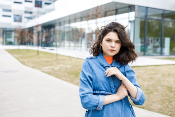 Young pretty girl walking on the street, dressed in jeans and denim shirt. Student weekdays