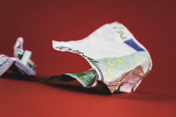 crumpled bill of one hundred euros and dollars lying on a red background