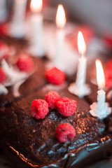 tasty homemade chocolate birthday cake decorated of some raspberries and candles served on the gentle pink background