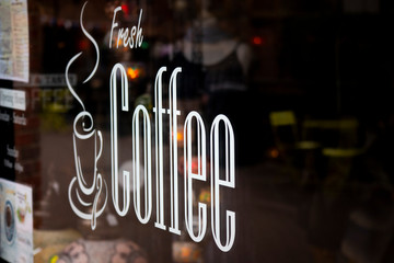 fresh coffee sign in cafe window with shallow depth of field