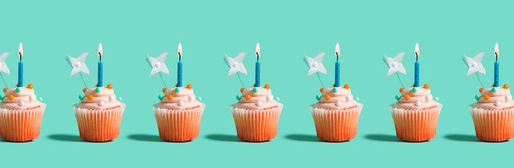 Tasty celebratory cupcakes with decorative lit candles