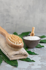 Body spa treatment bamboo brush with bath towel, salt m on green tropical leaf background
