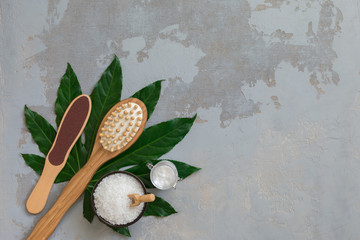 Fototapeta na wymiar Body spa treatment bamboo brushes with bath towel, salt and cream on green tropical leaf background