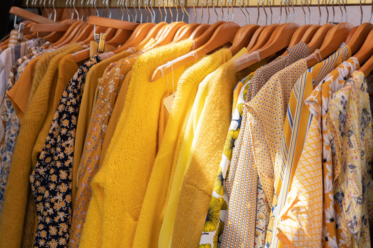 yellow colored clothes on hangers in retail shop Fashion and shopping concept