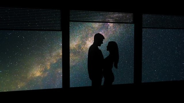 The man and woman standing near a window on a starry sky background. time lapse