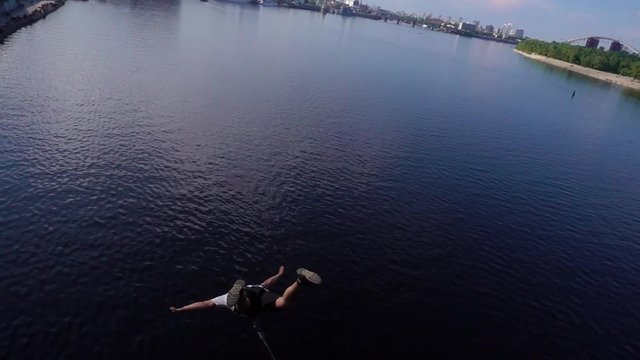 A man jumps from a bridge tied to a rubber band