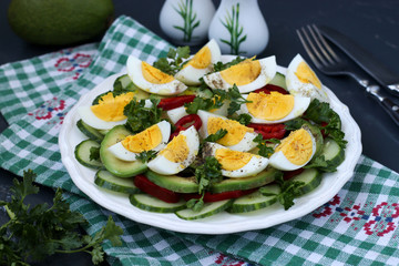 Healthy salad of avocado, cucumbers, eggs and sweet pepper located in a plate