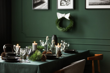 Christmas garland and black and white posters on green wall of dining room set for christmas dinner