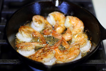 Shrimp Scampi cooking in a cast iron pan on the stove.