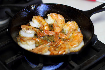 Shrimp Scampi cooking in a cast iron pan on the stove.