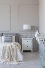 Simple white lamp on wooden night stand table with two drawers next to comfortable king size bed...