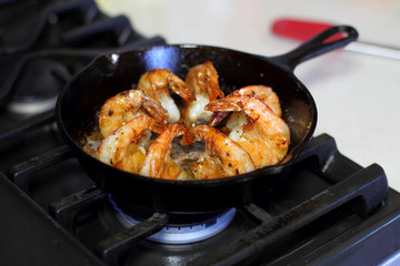 Shrimp Scampi cooking in a cast iron pan on the stove.