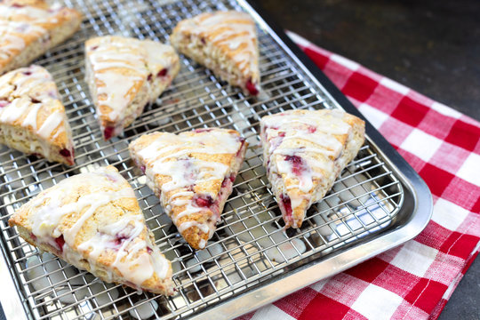 Freshly Baked Strawberry Scones on Cooling Rack with Red and White Checked Napkin Beside on Black Background