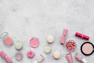 decorative cosmetics for make-up with macaroon cookies on gray stone tabletop background mock up