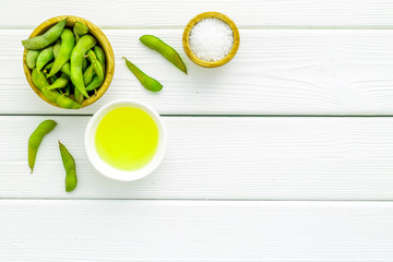 Fresh edamame and oil on white wooden background top view mock up