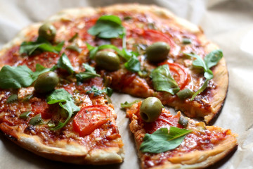 Homemade vegetarian pizza with tomato sauce, two types of cheese, tomatoes, peppers, arugula, olives and herbs. Selective focus.