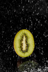Kiwi with splashing water on black background. Citrus fruit with water drops. Healthy freshness food. Green fruit with vitamin