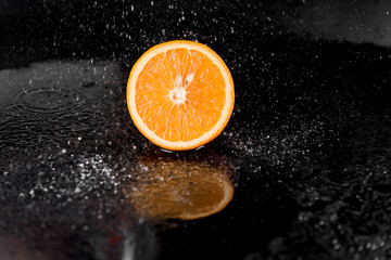 Fototapeta na wymiar Orange with splashing water on black background. Citrus fruit with water drops. Healthy freshness food. Green fruit with vitamin